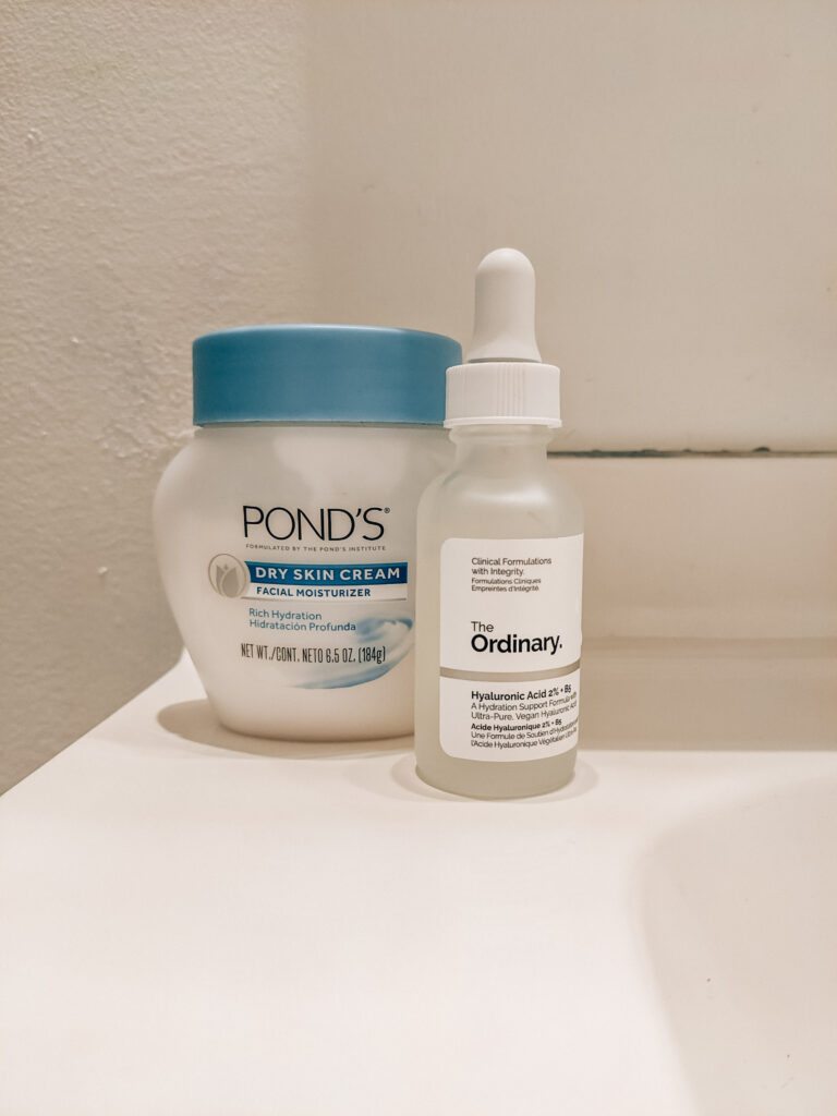 Two budget-friendly summer skincare products in my nighttime skincare routine: short squat white and blue jar of Pond's Dry Skin Cream, and The Ordinary Hyaluronic Acid.